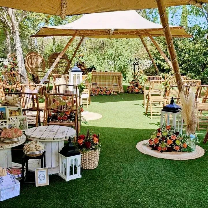 Ceremonia al aire libre decorada con cestas de flores, farolillos y detalles para los invitados